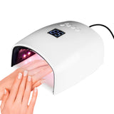 Two hands inside the White Joiken 48W 2-in-1 LED/UV Gel Nail Lamp displaying a digital timer on top, featuring a wide ergonomic opening and removable grey base plate for pedicure and manicure access.